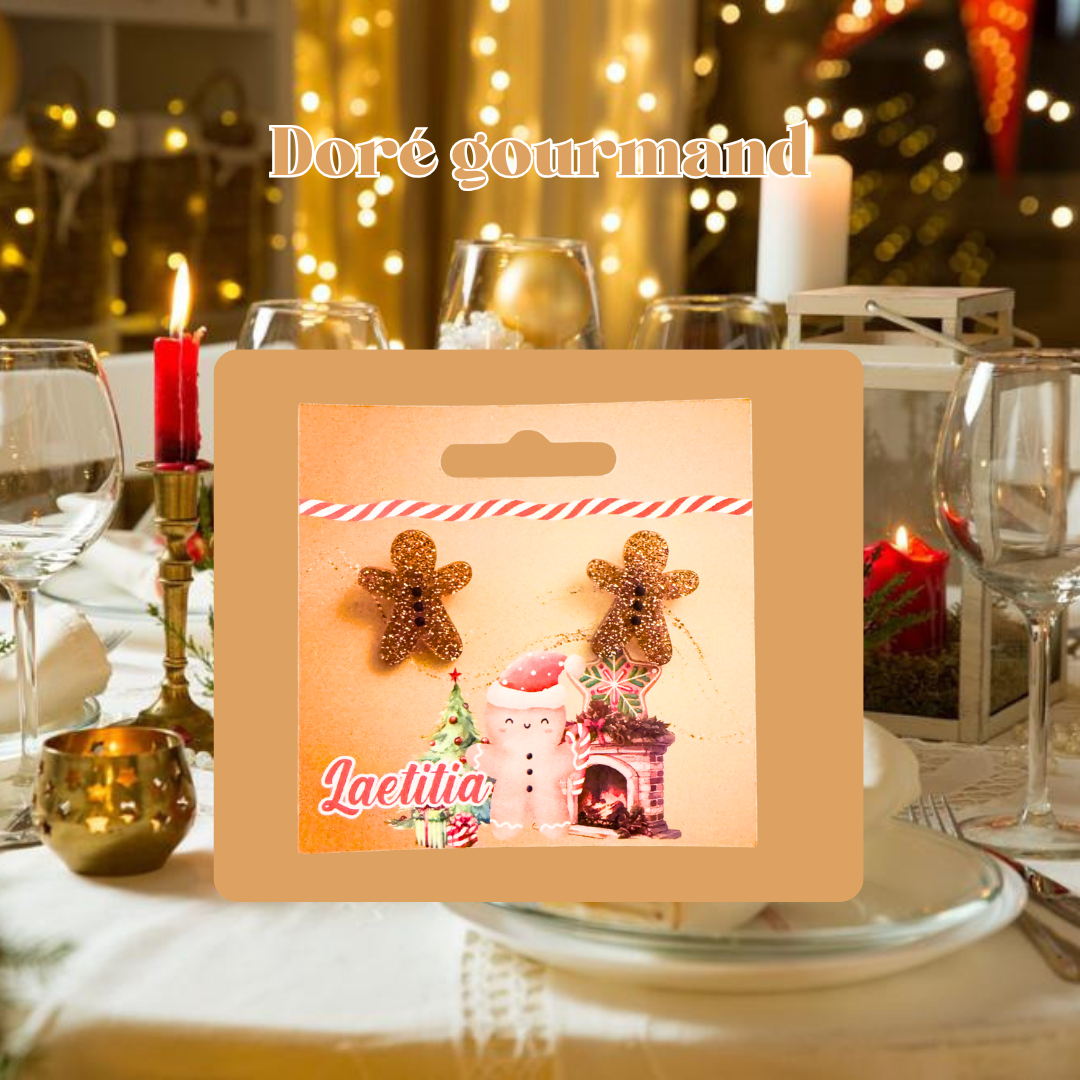 Boucles d'oreilles de Noël personnalisées, en forme de bonhomme en pain d'épice. Joliment présentées sur une carte personnalisée avec le prénom, sur le thème un thème doré et gourmand.